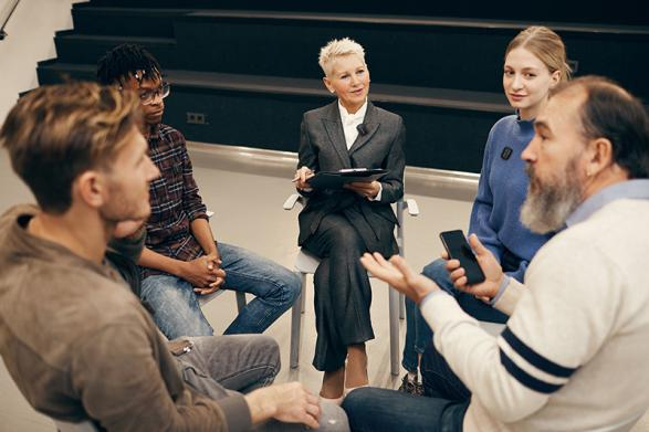 A group of people in a meeting, with one person holding a smartphone and a wireless microphone in use.